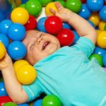 Bébé qui s'amuse et rigole dans des balles multicolores à la crèche