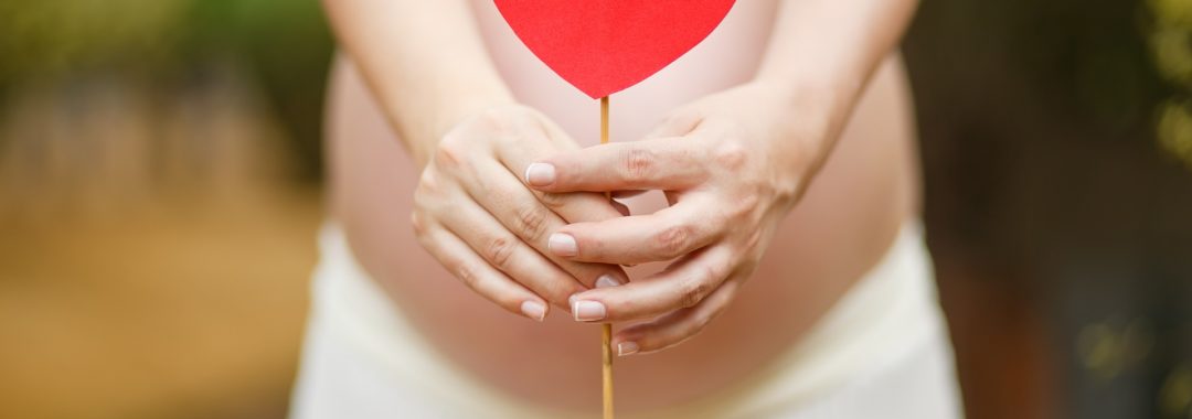 Femme enceinte avec un coeur rouge