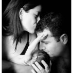 Photo en noir et blanc d'une chaine de bisous entre bébé et ses parents