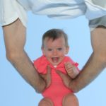 Photo souvenir de bébé dans les bras de son père en contre plongée